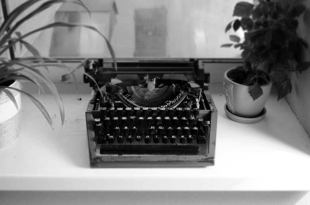 Vintage typewriter on a wooden desk with scattered manuscript pages
